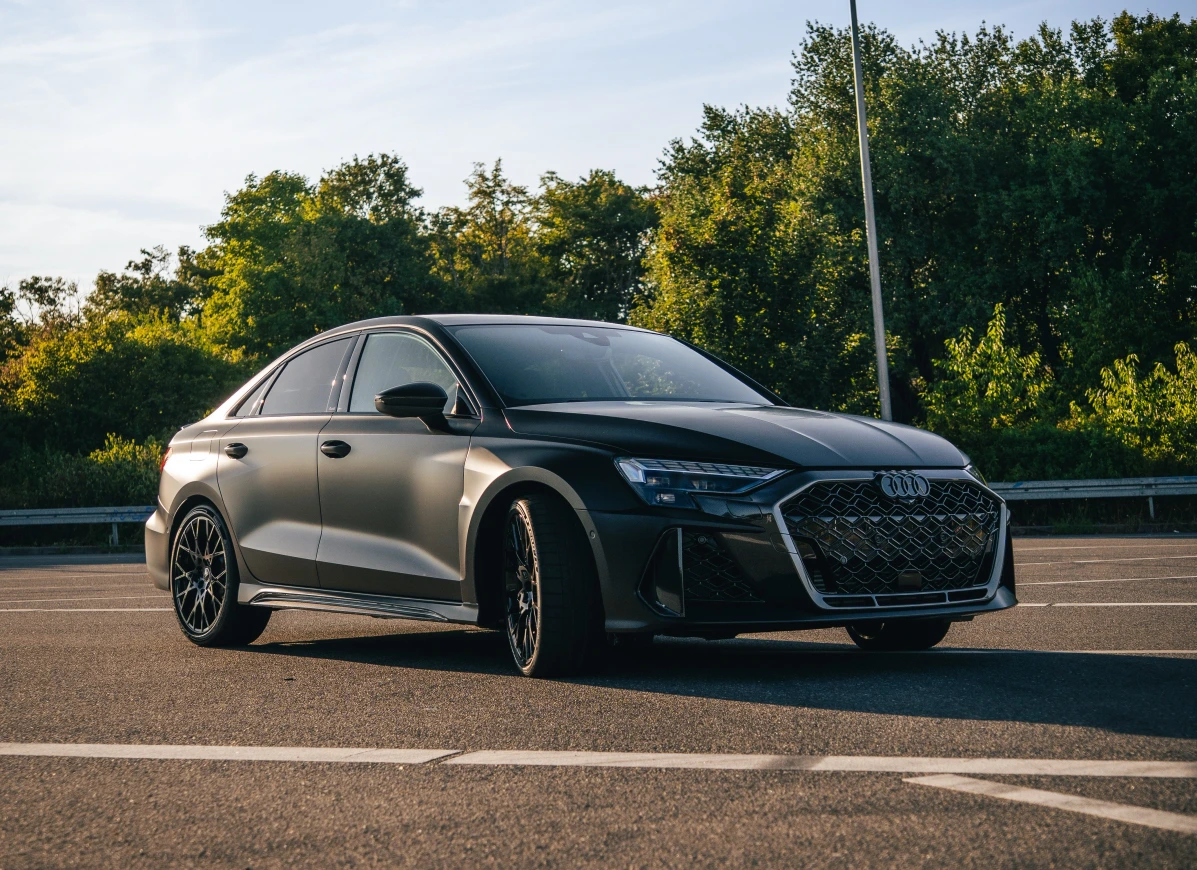 Audi RS3 2025 in schwarz Matt seitlich fontal auf einem Parkplatz